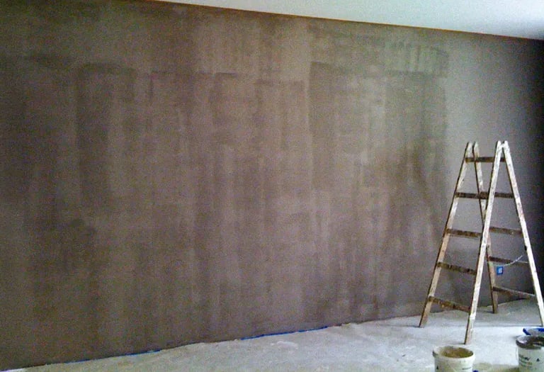 Taupe-coloured wall prepared for decoration with hand-painted art, a dropcloth and ladder