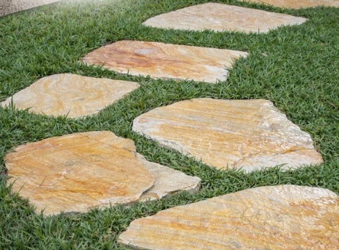 pedra são tomé lajão amarelo colocado na grama do jardim, pisante de passagem, material rústico
