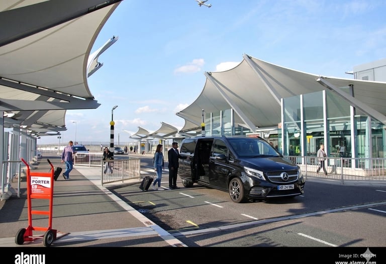 Black Mercedes GLS 450 SUV - chauffeur picking up a passenger at an airport terminal entrance.