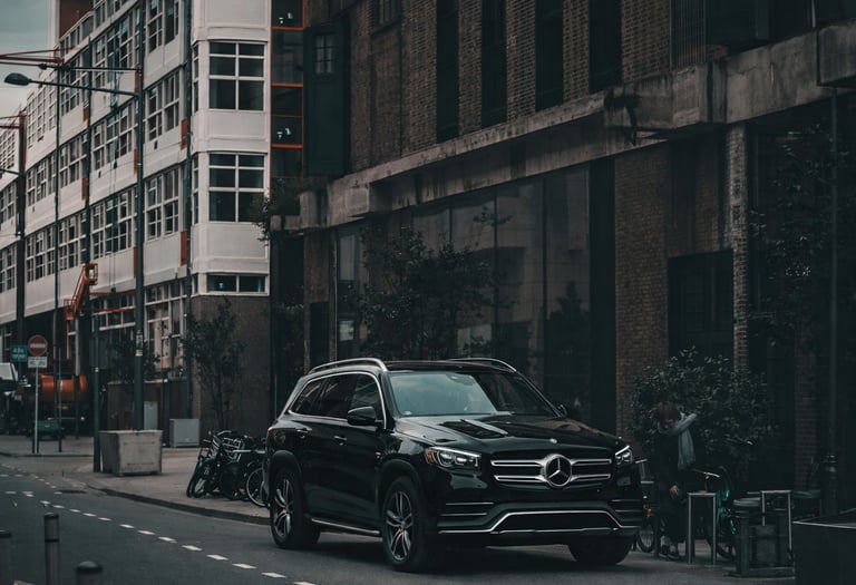 A black Mercedes-Benz SUV parked on a city street in front of industrial brick buildings.