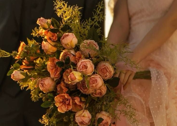 Novia con ramo de rosas en tonos durazno y verde.