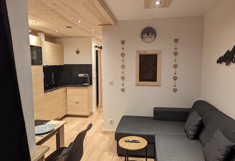 Open living space inside a warm Val Thorens ski apartment with lounge area, dining table and modern mountain kitchen