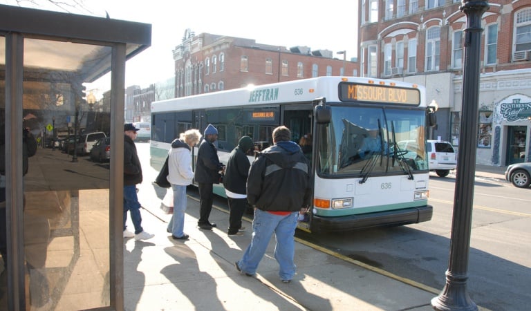 A group of people at a bus stop boarding a Jefferson City bus