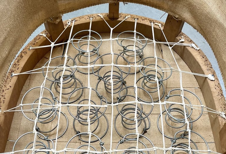 Carcasse d'un fauteuil crapaud avec sur le sanglage des ressorts guindés par des cordes