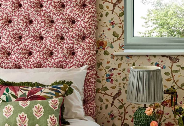 Une chambre avec un lit et une tête de lit capitonnée et deux coussins près d'une table de chevet