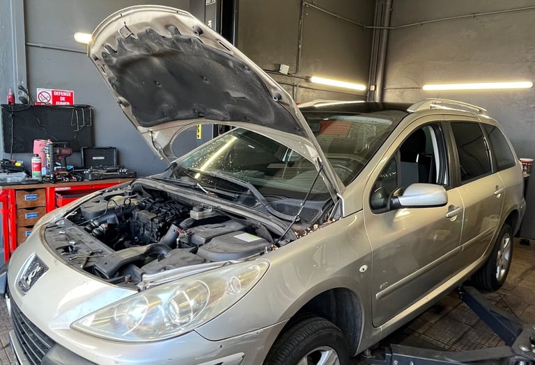 a car with a in a garage with mechanics working on it