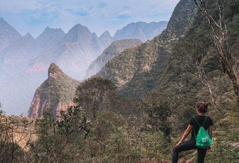 Uma pessoa de costas olhando para os vales no topo da montanha.