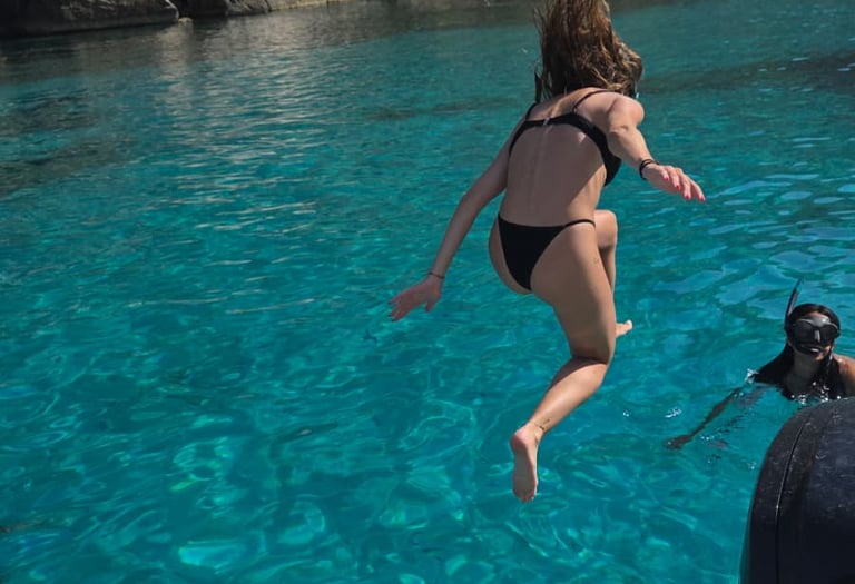 une jeune femme sautant dans la mer depuis un bateau