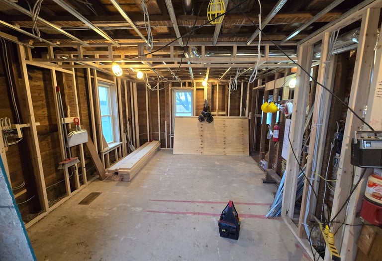 Interior view of a home basement renovation featuring wood stud framing and exposed ceiling joists.