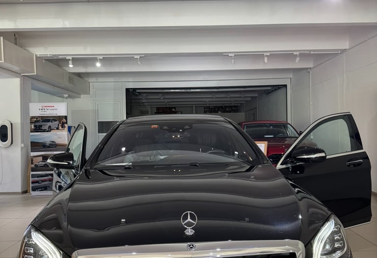Black Mercedes S-Class with open doors in the hall of a carselling Store