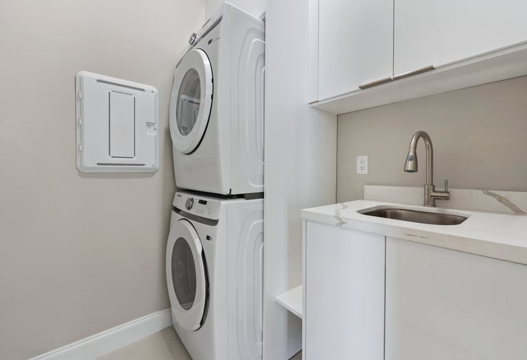 Laundry with stack washer and dryer, sink and lots of storage cabinet