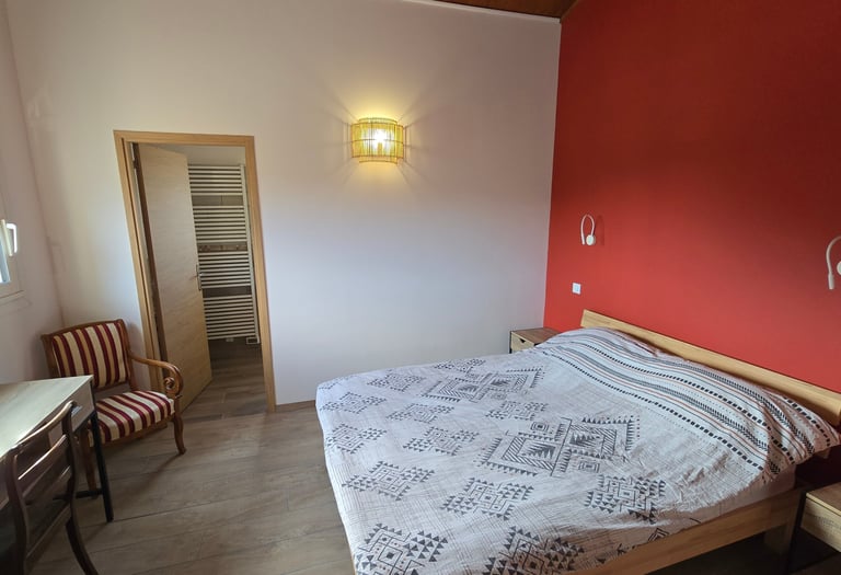 Chambre d'hôtes refaite à neuf avec lit double, chaise et bureau.