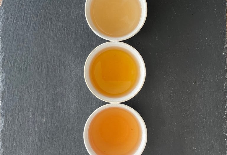 Tasses alignées contenant différents types de thés.