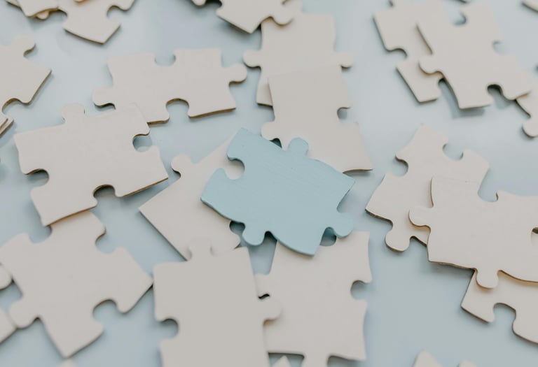 Witte puzzelstukjes met één blauw stuk als metafoor voor sturen en verbinden in moreel beraad.