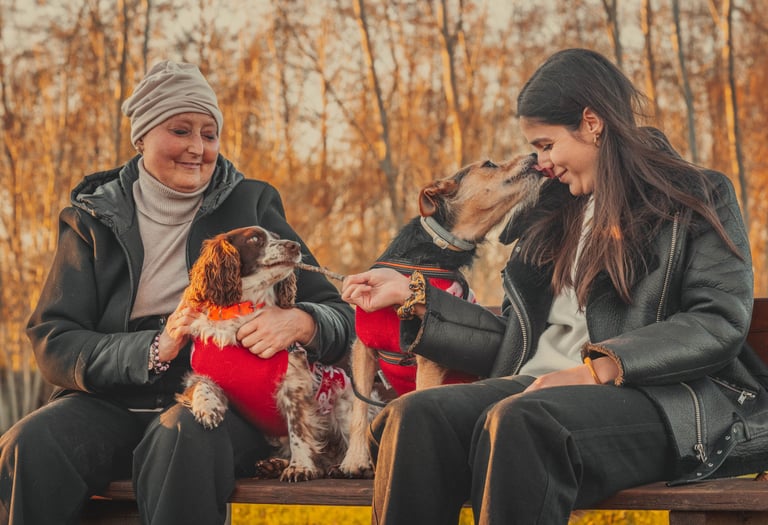 ragazza che gioca coi cani e la mamma sedute su una panchina
