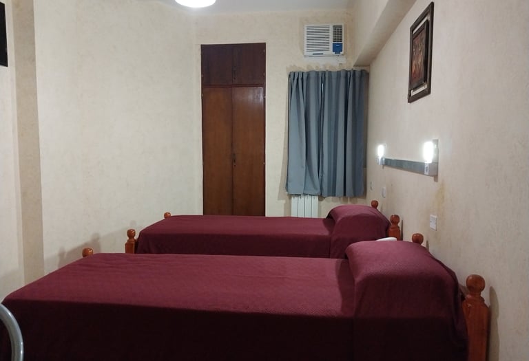 Una habitación con 2 camas y un ventilador.