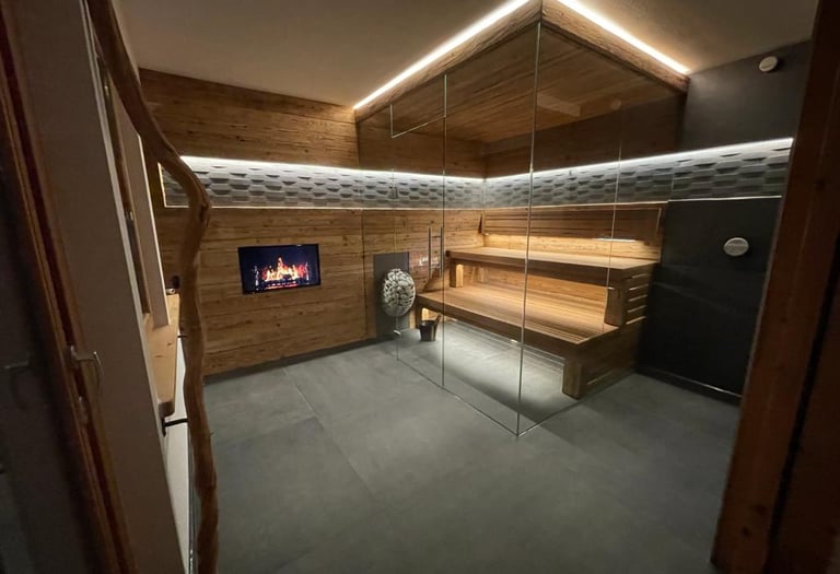 Moderne Innensauna mit Eckverglasung, ausgestattet mit rustikaler Holzverkleidung und indirekter LED-Deckenbeleuchtung