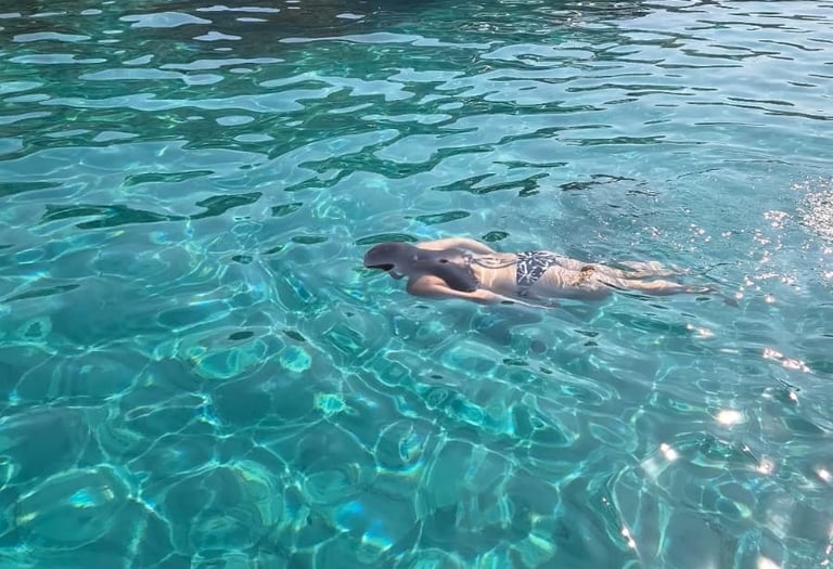 Jeune femme nageant dans une eau turquoise.