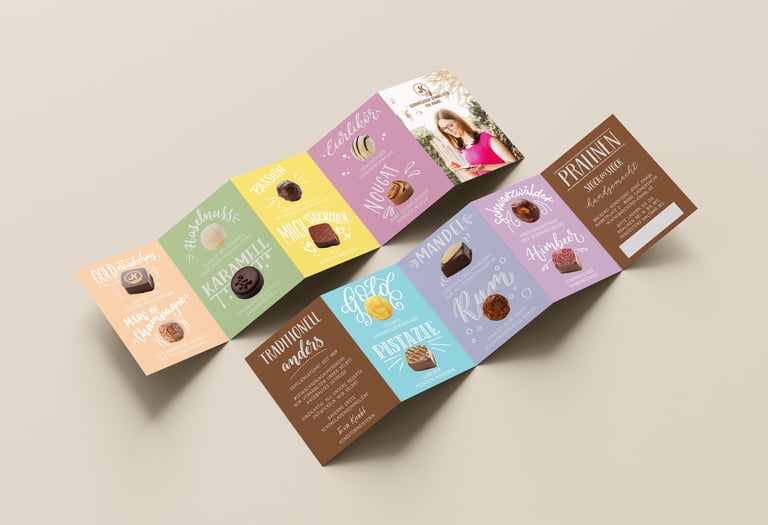 A colorful accordion-fold chocolate menu showcasing gourmet pralines, including pistachio and champagne truffles.