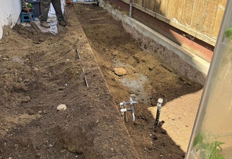 Professional landscaper preparing soil and installing mesh for a residential backyard garden bed in 