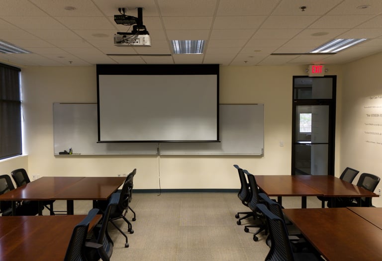 a classroom room with a projector screen and a projector