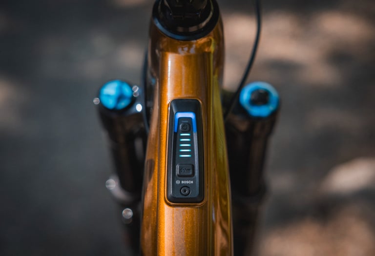 Close-up of a Bosch System Controller integrated into the top tube of an orange e-bike frame.