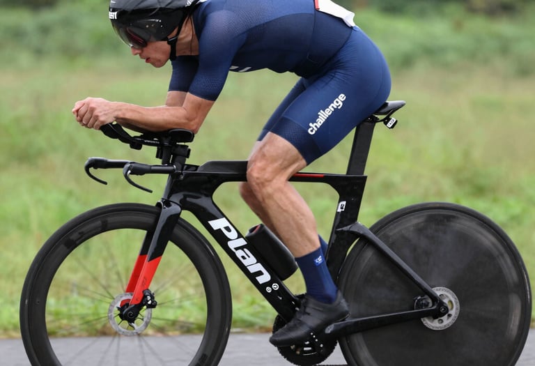 Close-up of cyclist in aerodynamic position on a time trial bike with dark and gold accents.