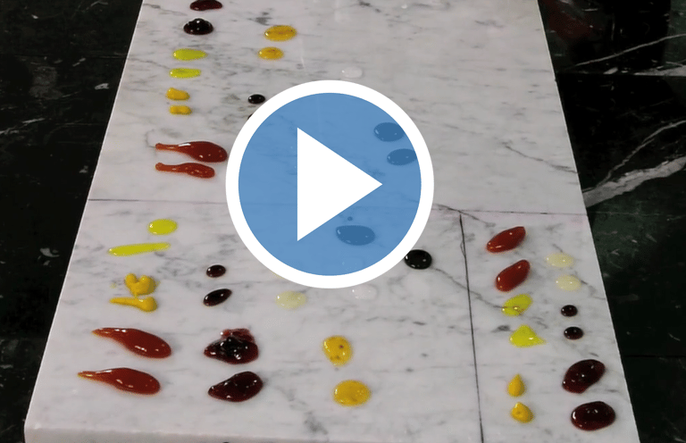 Drops of colorful culinary sauces and glazes arranged on a white marble slab for stain testing.