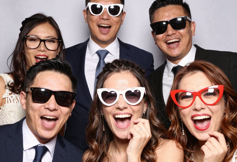 Guests at a birthday party laughing and posing with playful photo booth accessories.