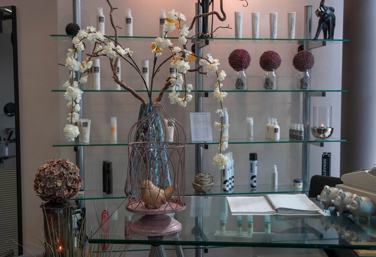 A boutique salon reception desk featuring white flowers in a birdcage vase and professional hair care products.