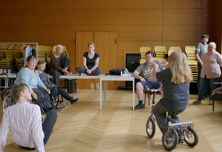 Menschen mit und ohne Behinderung unterhalten sich in einem Saal