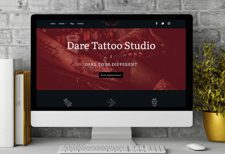 a computer screen on a desk showing the home page of a tattoo studio on the screen