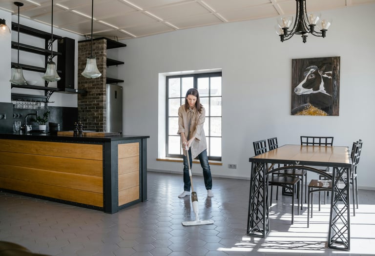 a woman in a kitchen with a mop cleaning the floor