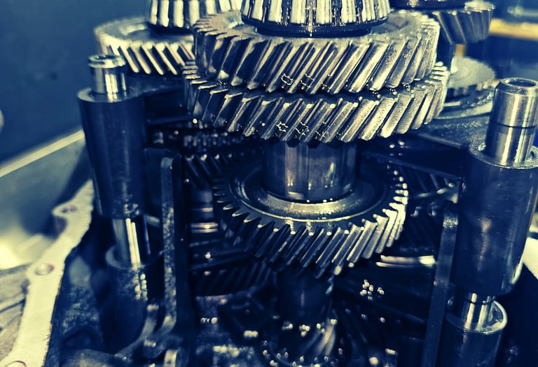 A detailed close-up of oily metal gears and planetary components inside a disassembled car transmission.