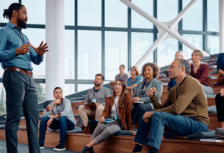 a man in a blue shirt and jeans standing in front of a crowd of people