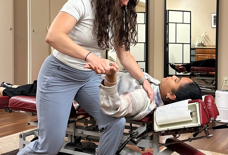 Chiropractor performing nerve tension test of arm with patient laying on back on chiro table. 