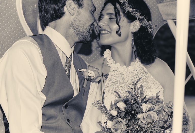 a bride and a groom kissing and smiling at each other in a carriage