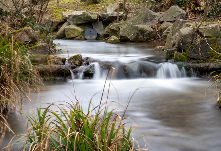 Bachlauf mit Langzeitbelichtung, weiches Wasser zwischen moosigen Steinen