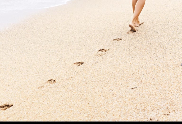 Voetafdrukken in zand op het strand bij de kustlijn.