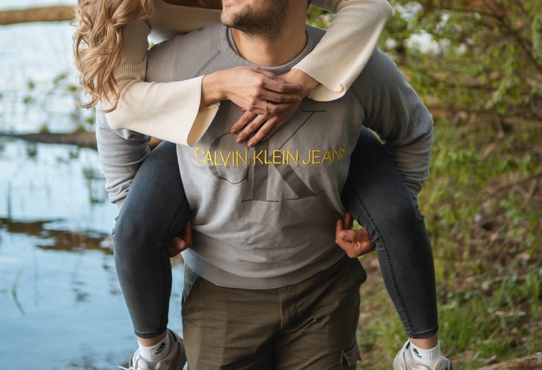 Glückliches Paar beim Huckepack am See. Authentische Paarfotografie von Joel Pingel.