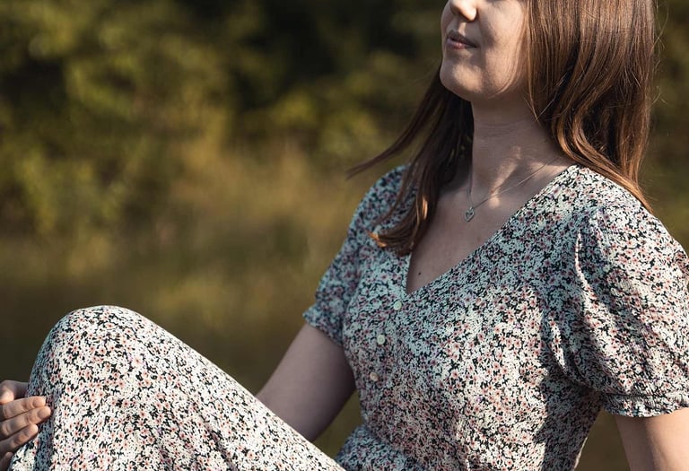 Frau im Blumenkleid sitzt entspannt in der Sonne. Natürliches Portrait von Just Perspectives.