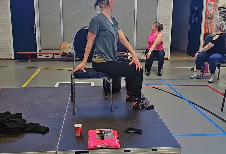 Dames in een zittende twist, op een stoel, in een gymzaal