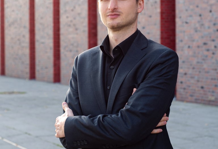 a man in a suit and tie standing in front of a brick wall