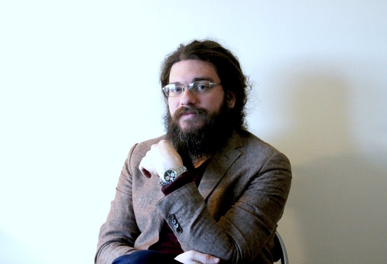 a man with a beard and glasses on a chair