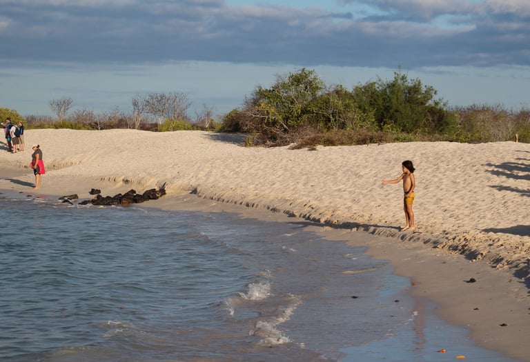 Child playing in the shallow turquoise waters of Tortuga Bay, Galápagos perfect for family-friendly