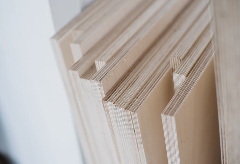 Stacked birch plywood sheets showing layered wood grain edges for carpentry and construction.