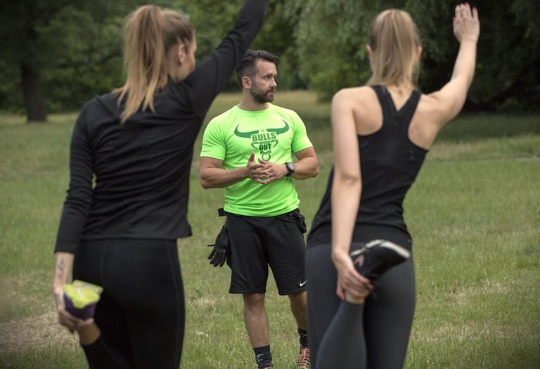 Trener stojący przed dwiema dziewczynami uprawiającymi stretching.