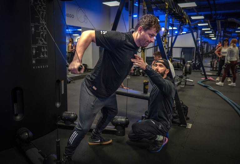 Trener instruuje podopiecznego gdy ten wykonuje ćwiczenie na siłowni.