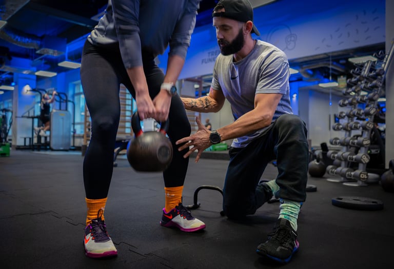 Trener instruuje kobietę przy treningu z kettlebell.