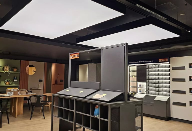 Modern Jotun paint showroom with backlit ceiling panels, color displays, and industrial shelving.